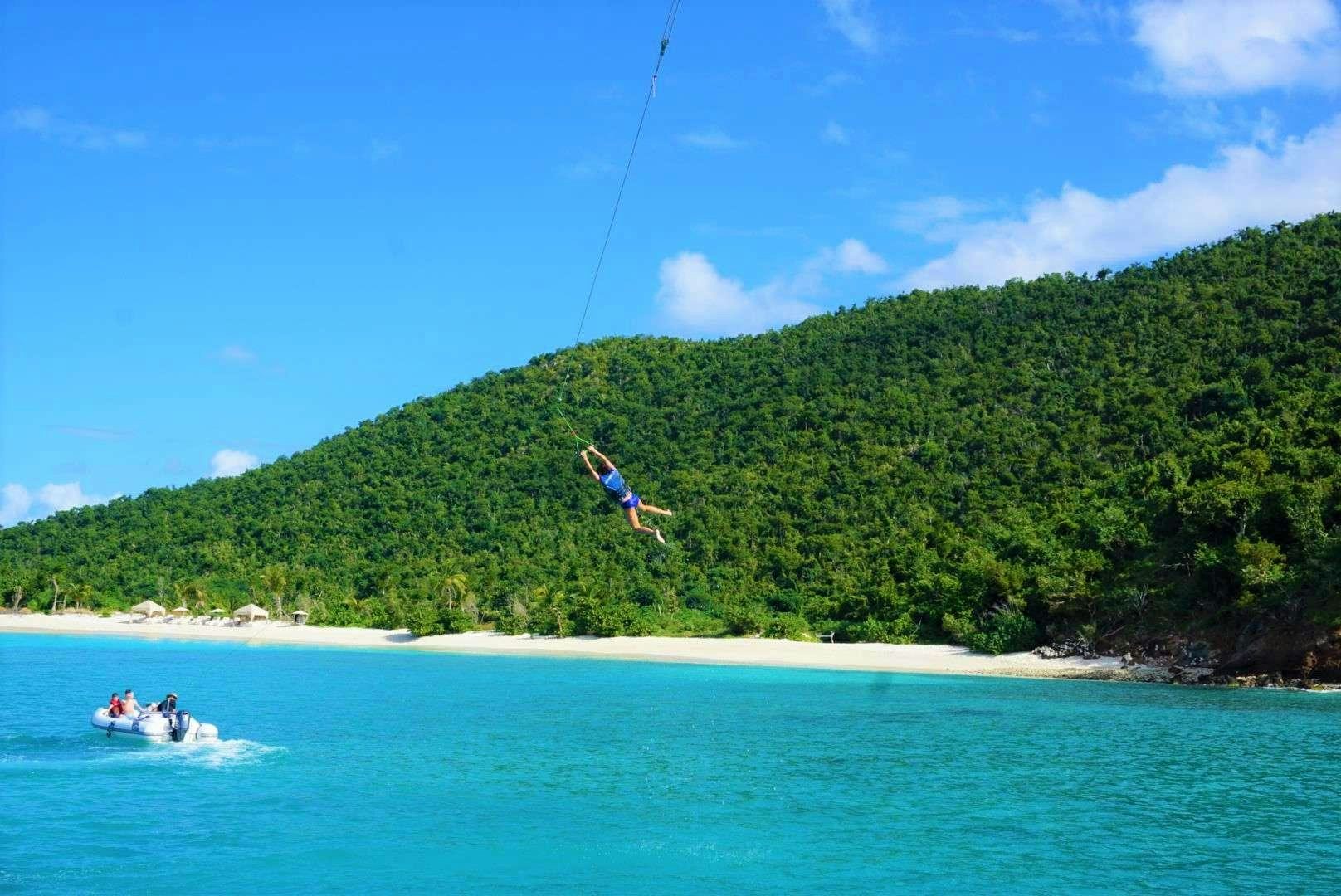 a kite surfer flies over a small boat aboard SERENITY NOW Yacht for Charter