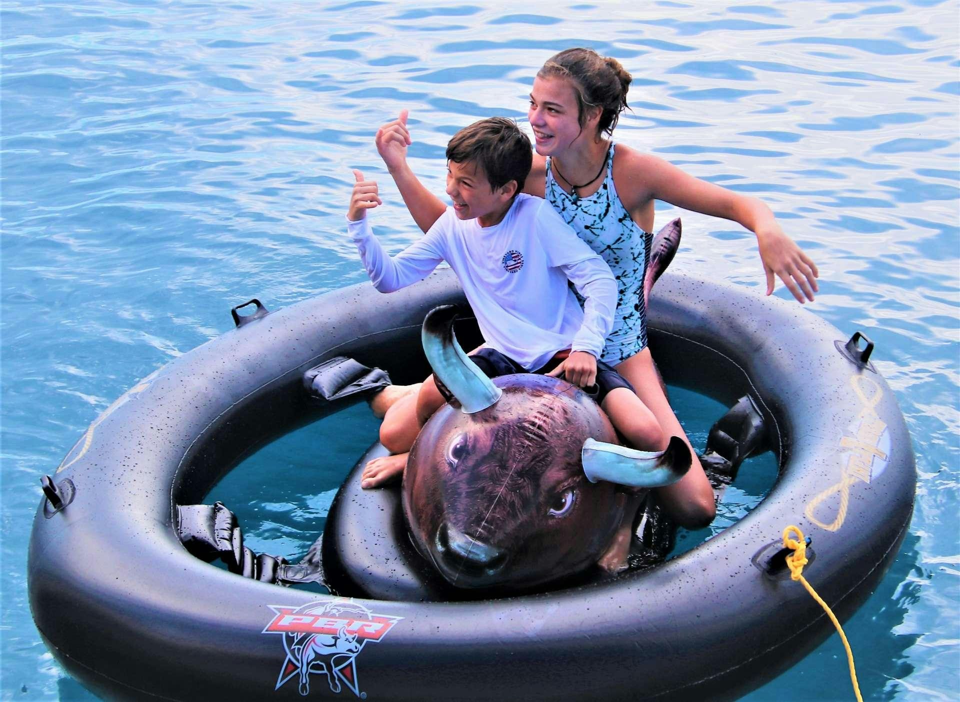 a man and a woman riding a dolphin in the water aboard SERENITY NOW Yacht for Charter