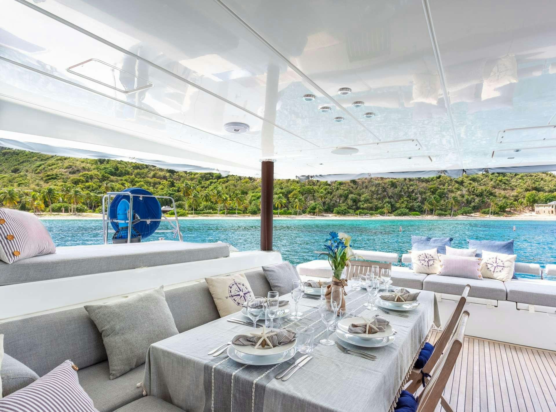 a table set for a meal on a deck overlooking a body of water aboard SERENITY NOW Yacht for Charter