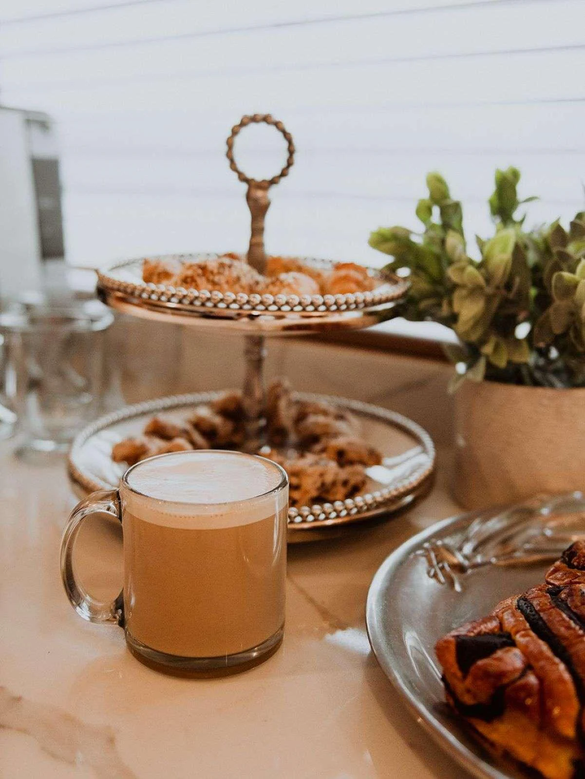 A close-up of a luxurious breakfast setup with a cappuccino and pastries on a yacht. aboard SKY Yacht for Charter