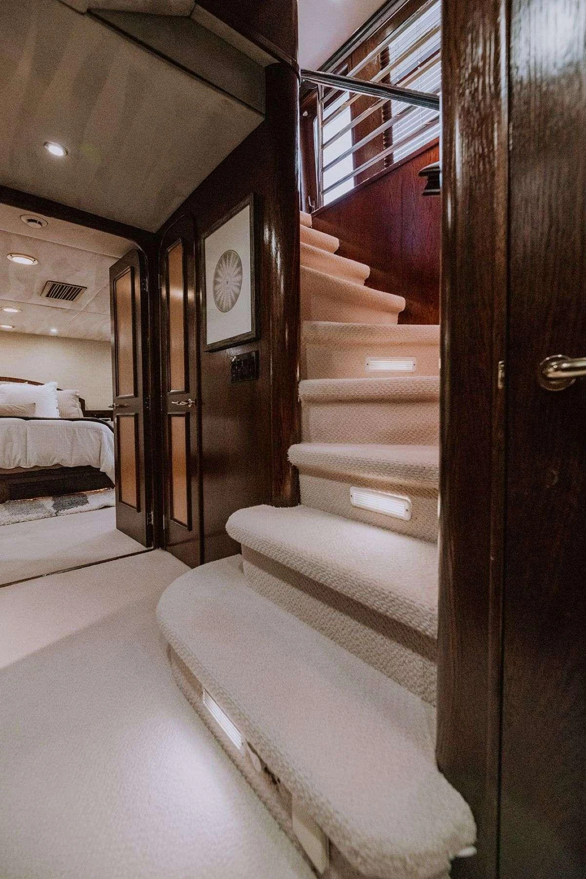 A luxurious interior staircase with soft lighting leads to an elegant stateroom. aboard SKY Yacht for Charter