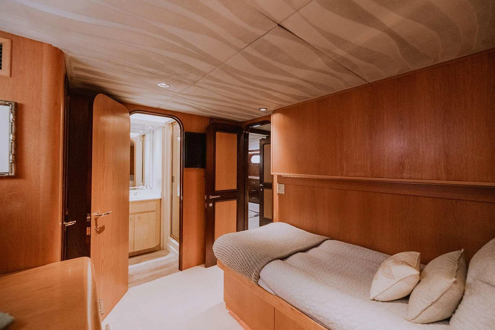 The guest cabin features a cozy single bed with warm wooden paneling and soft lighting. aboard SKY Yacht for Charter