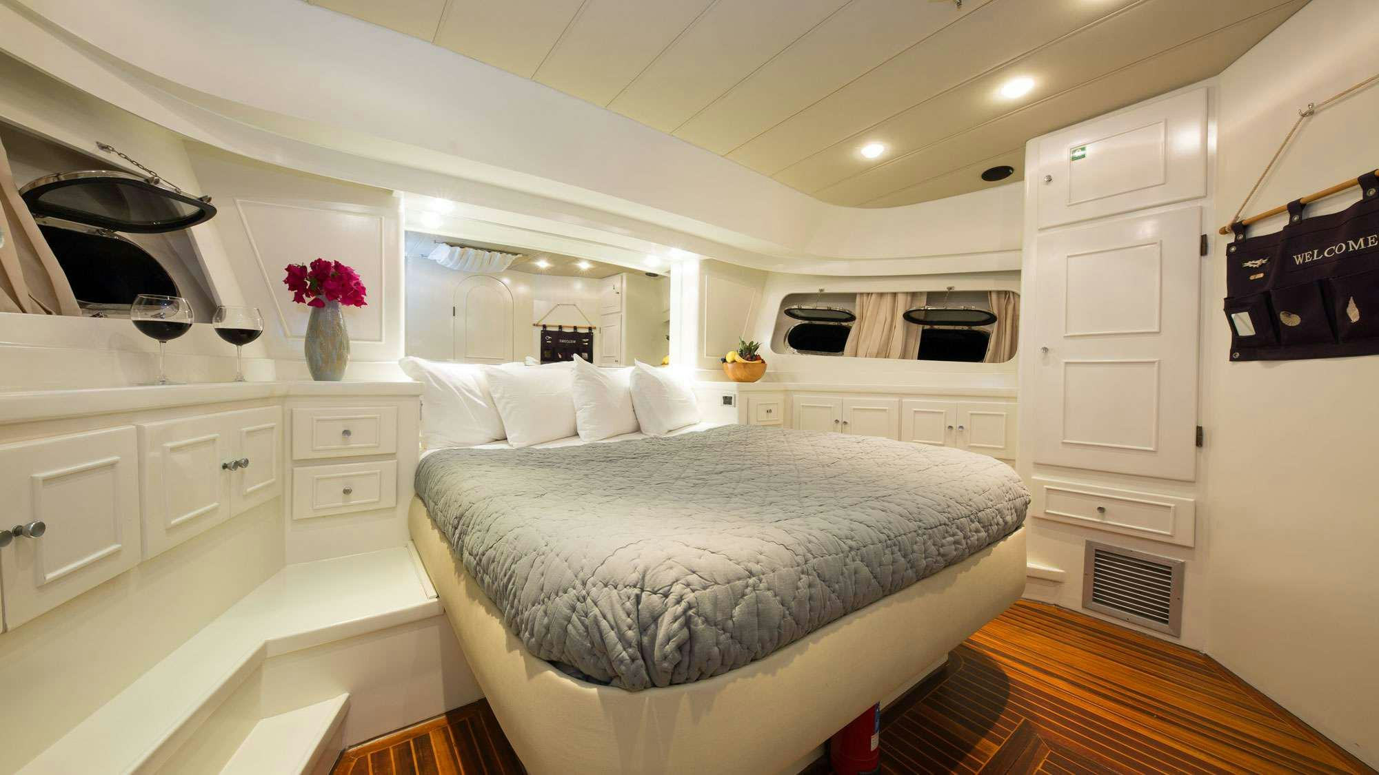 a large white bedroom with a large bed and white cabinets aboard SERENITY 70 Yacht for Charter