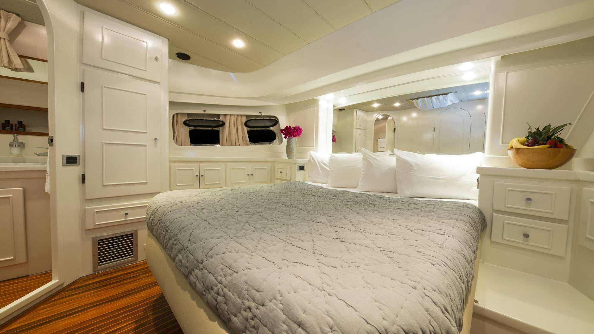 a large white bedroom with a large bed and white cabinets aboard SERENITY 70 Yacht for Charter