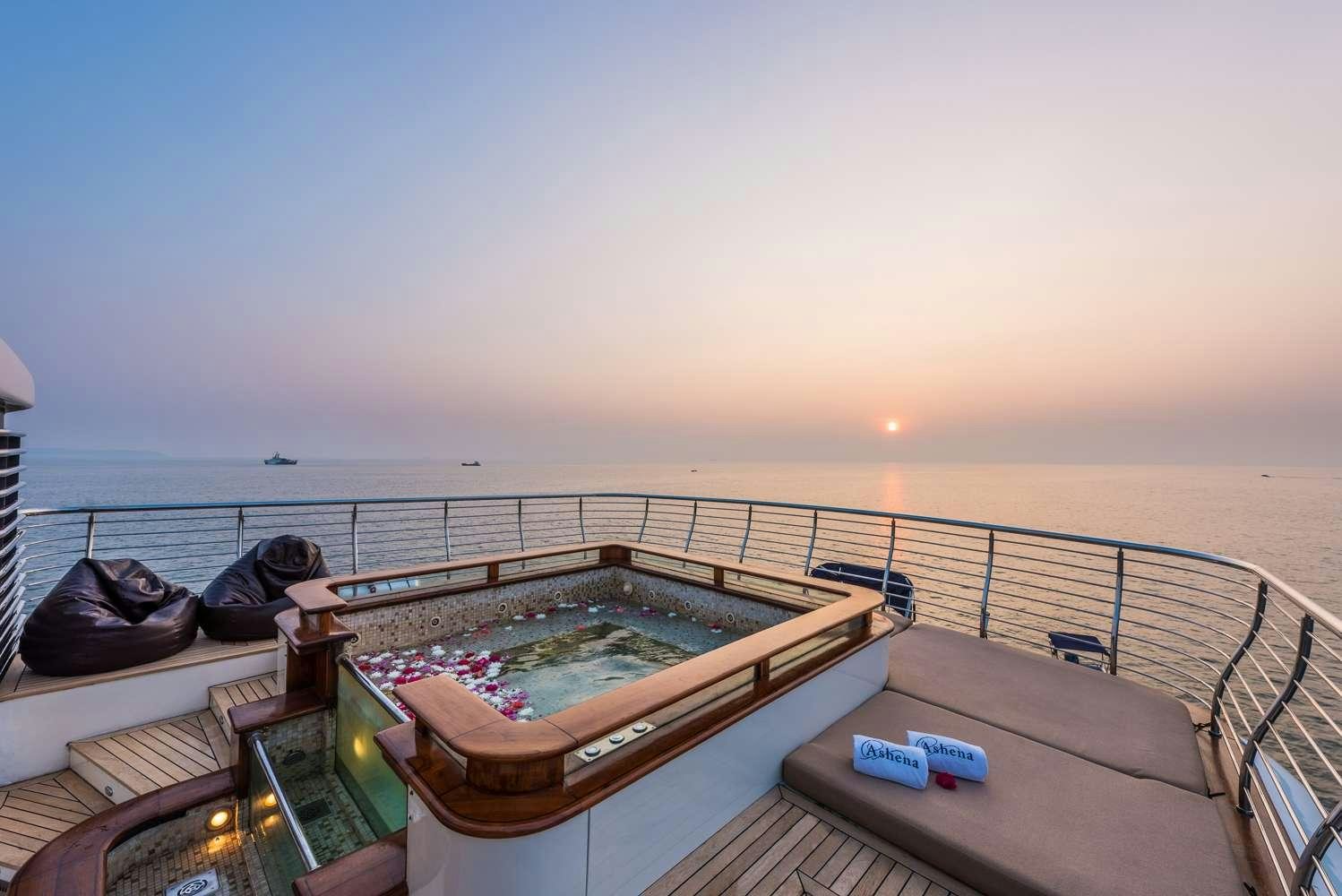 a person lying on a deck with a pool and a large body of water in the background aboard ASHENA Yacht for Charter