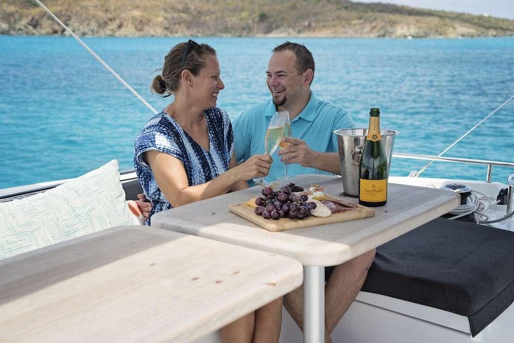 a man and a woman sitting at a table with a pizza and a bottle of beer on it aboard SOUTHERN COMFORT Yacht for Charter
