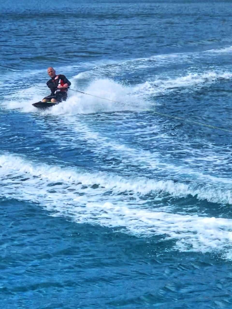 a man surfing on the waves aboard STARFISH Yacht for Charter