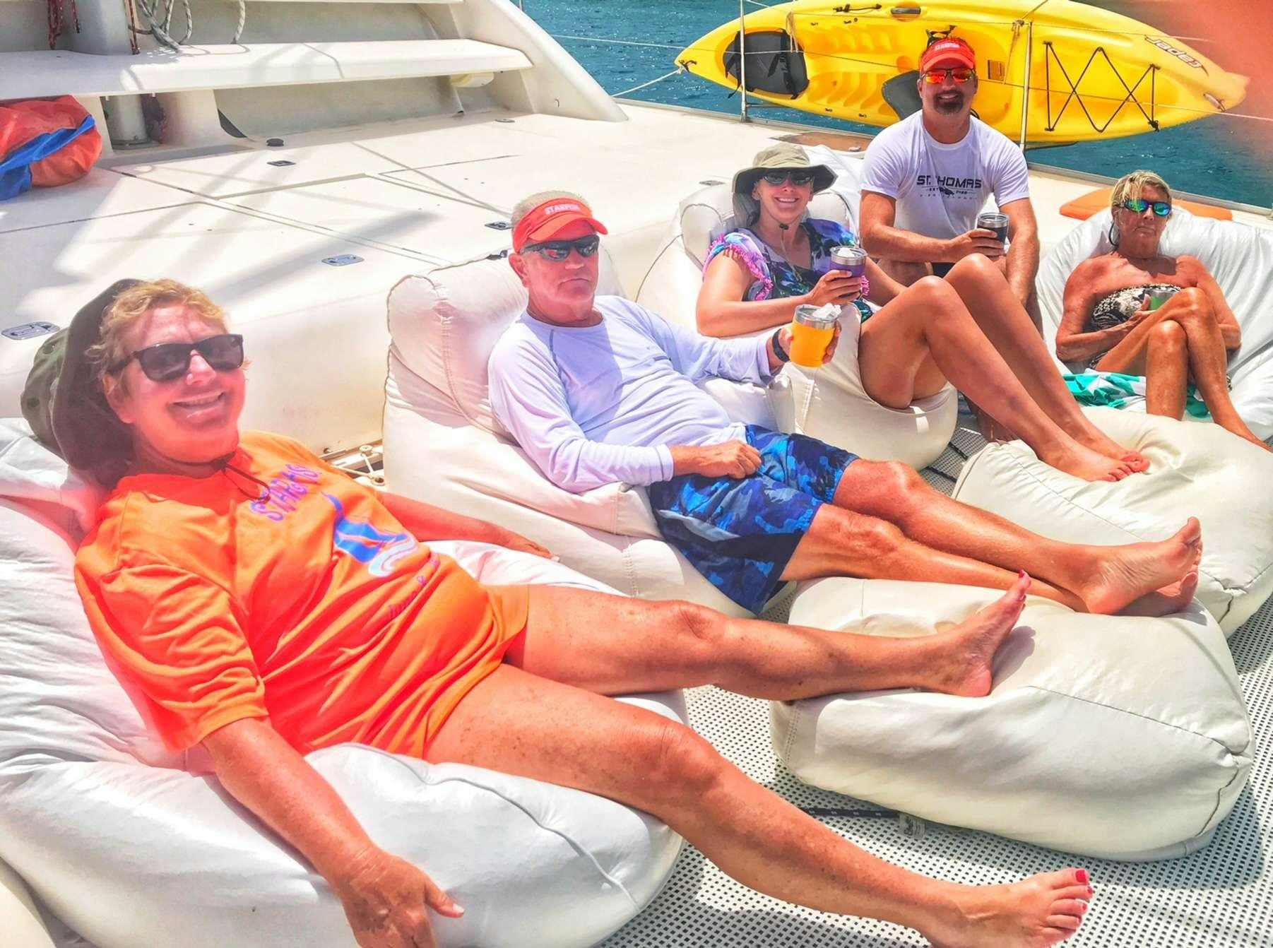 a group of people sitting on lounge chairs on a beach aboard STARFISH Yacht for Charter