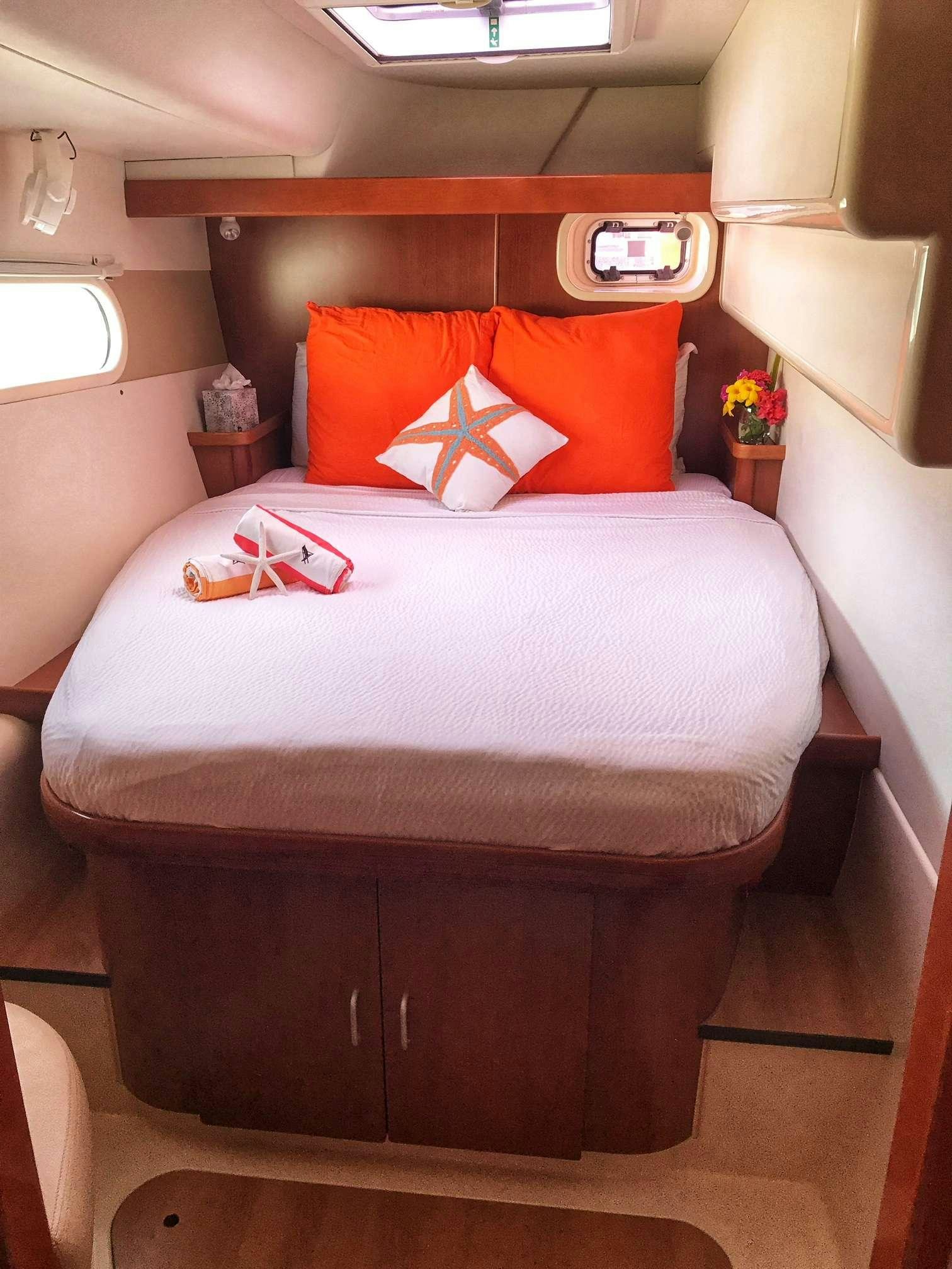 a bed with a white comforter and orange pillows aboard STARFISH Yacht for Charter