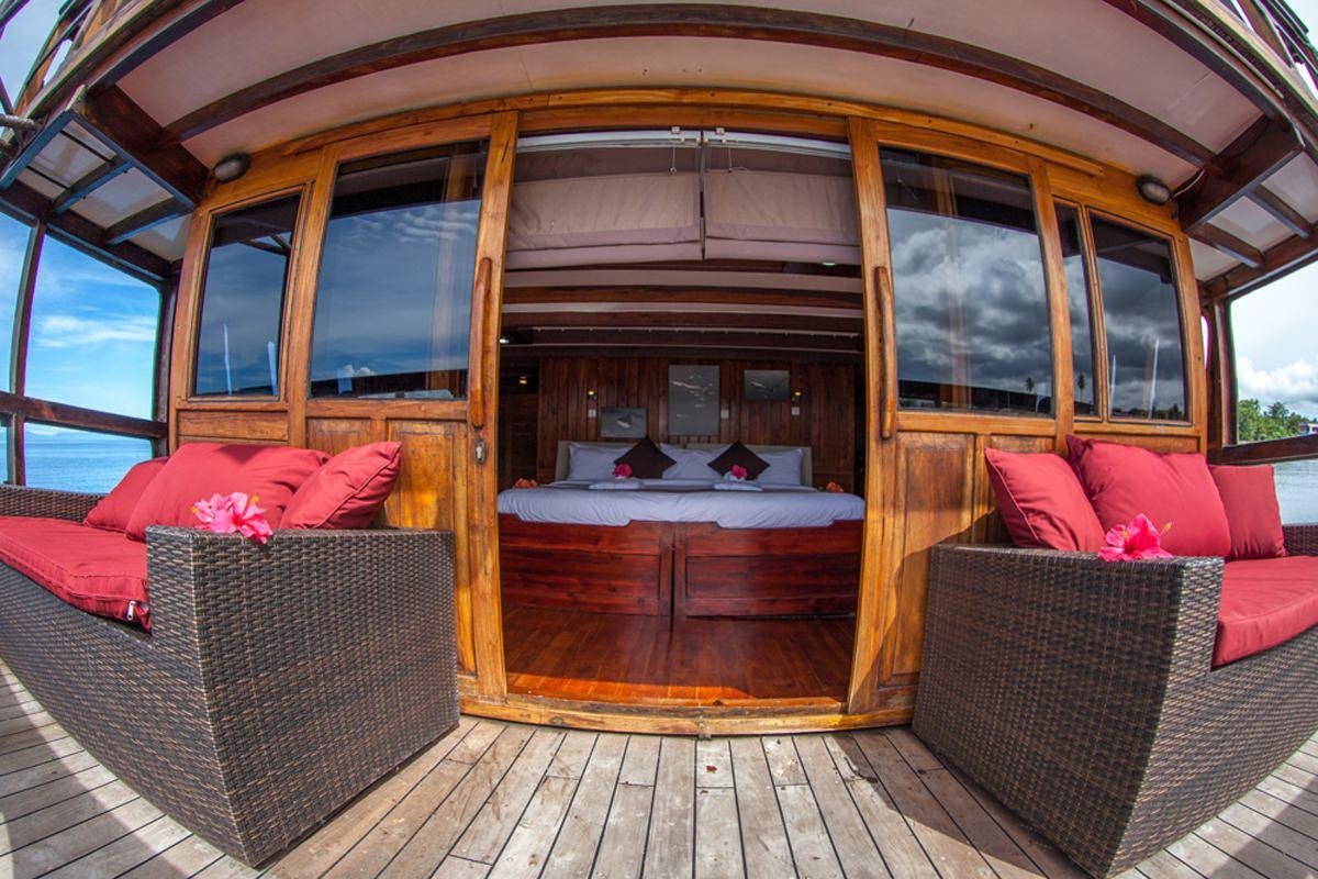 a cabin with a bed and a couch aboard DAMAI Yacht for Charter