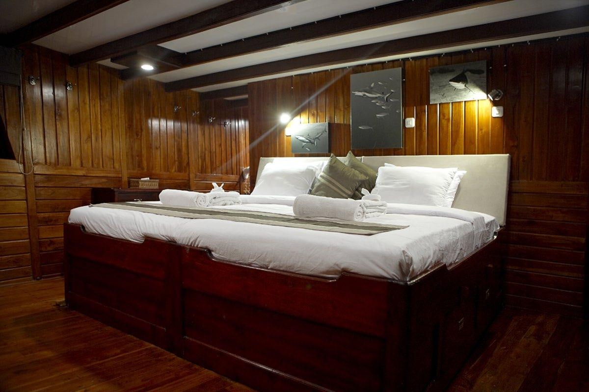 a room with a bed and a wood wall aboard DAMAI Yacht for Charter