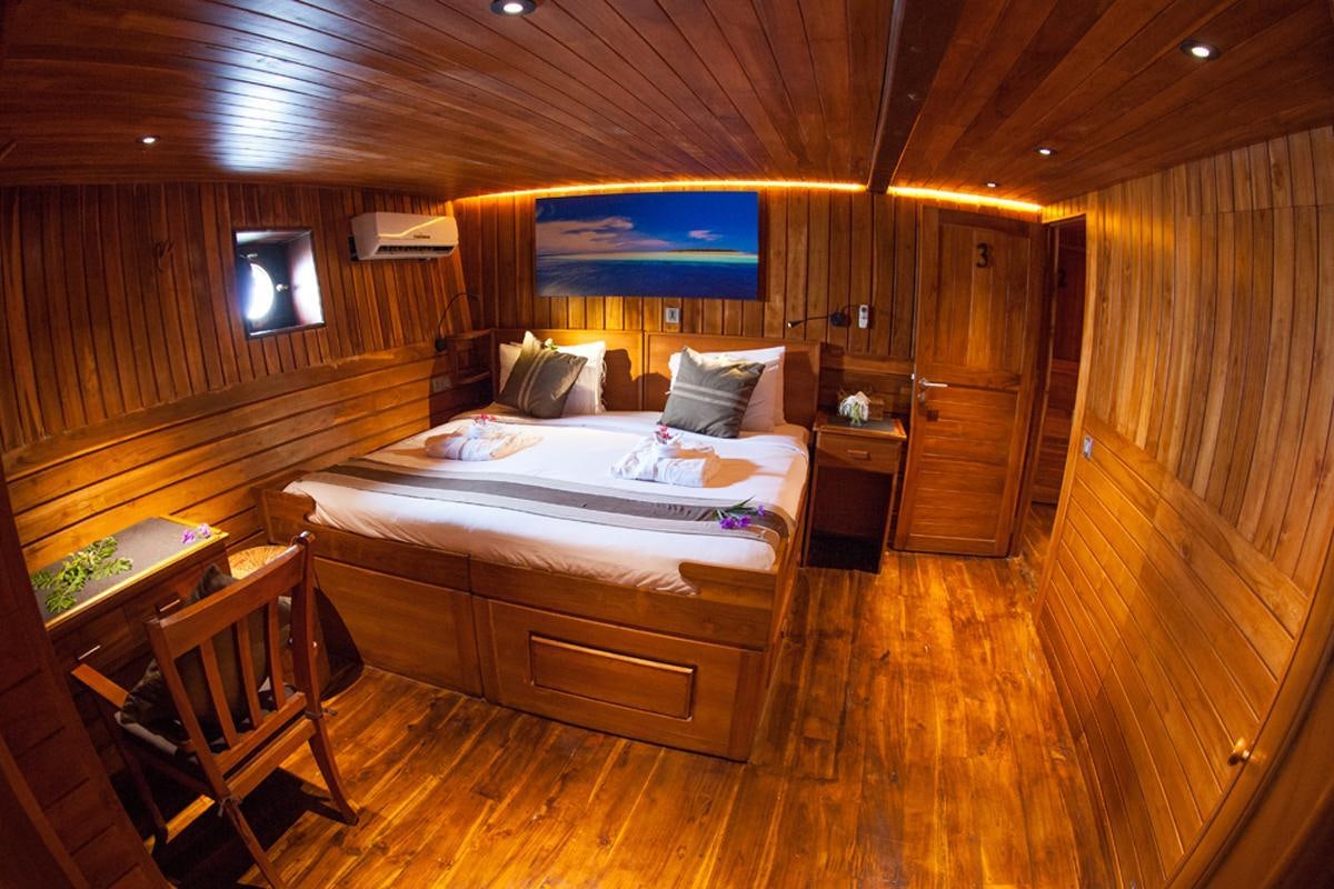 a room with a bed and a television aboard DAMAI Yacht for Charter