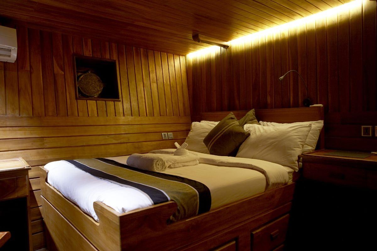 a bed with a wood wall aboard DAMAI Yacht for Charter