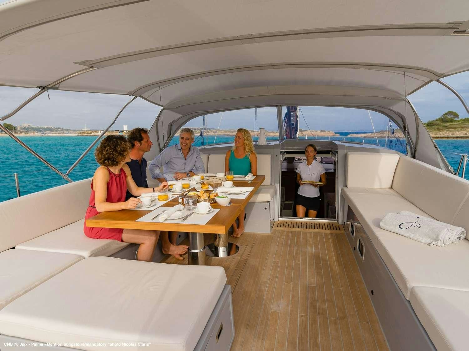 a group of people sitting at a table on a boat aboard J SIX Yacht for Charter