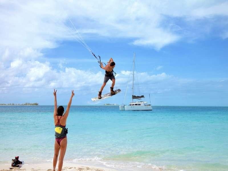 a couple of people jumping into the water with a sailboat in the background aboard Madrigal V Yacht for Charter