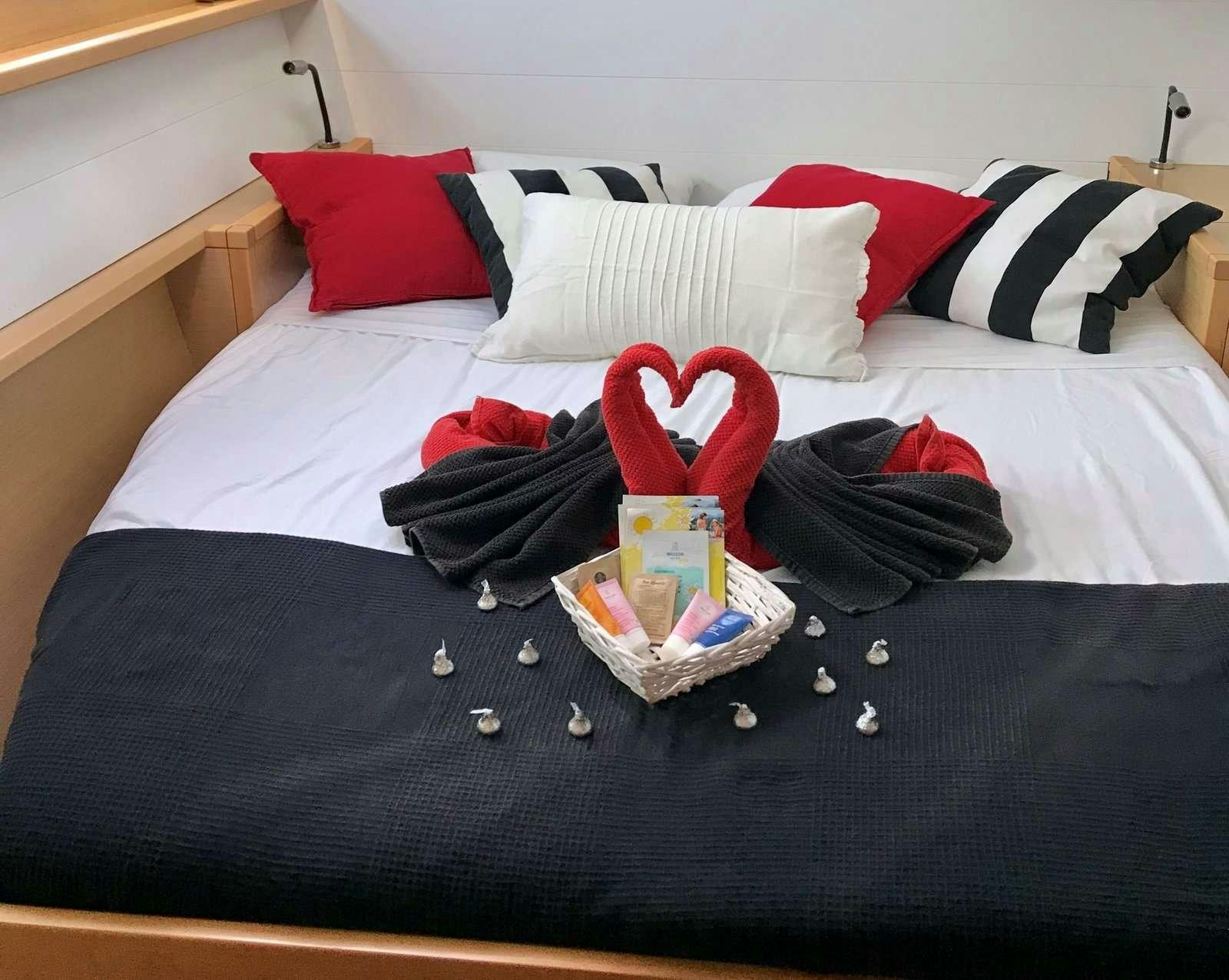 a bed with a black blanket and red and white pillows aboard Madrigal V Yacht for Charter