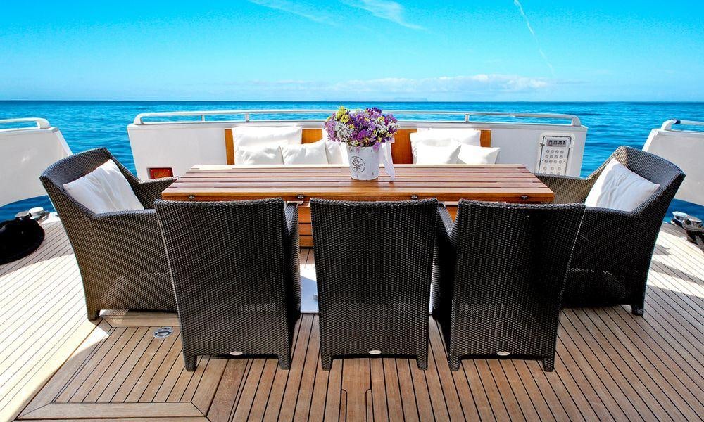 a table set with chairs and a vase of flowers on a deck aboard TROPICANA Yacht for Charter