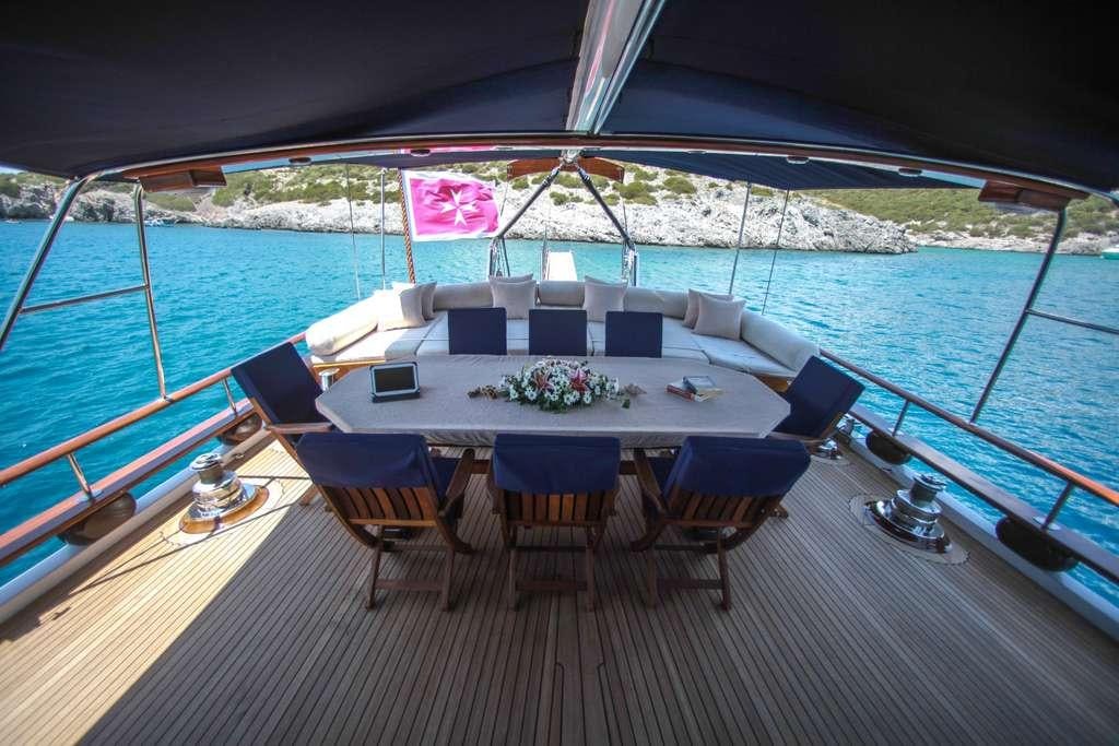 a table on a deck with chairs and a pool in the background aboard AREA Yacht for Charter