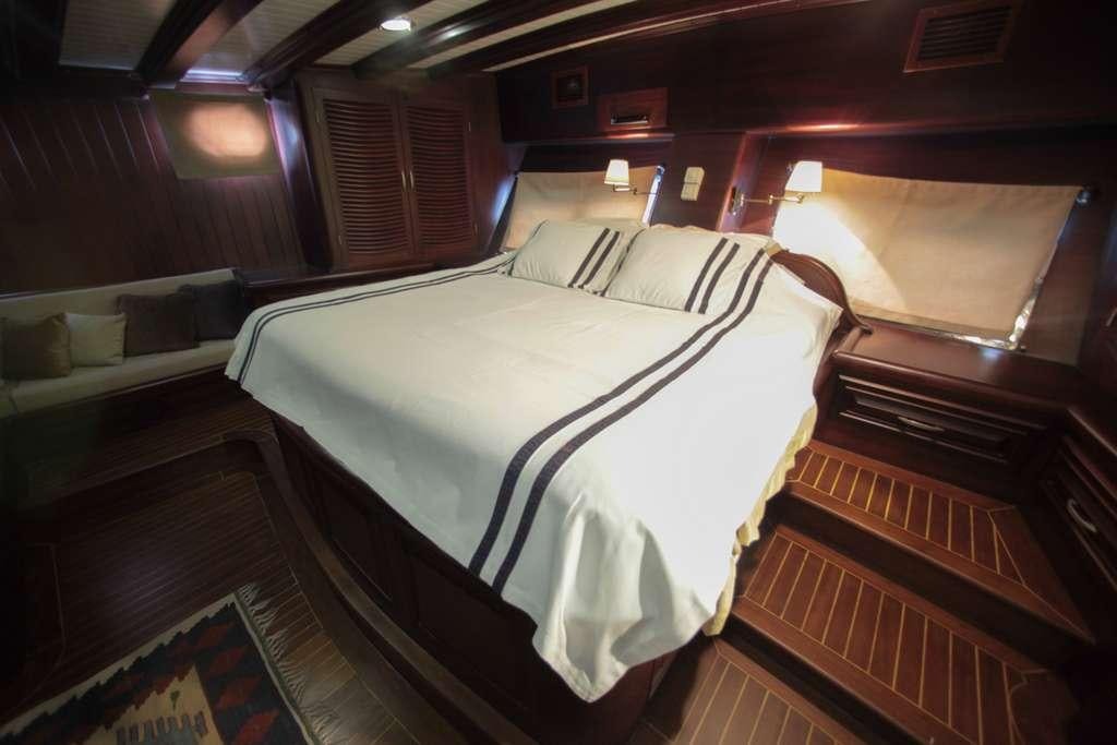 a room with a bed and couch aboard AREA Yacht for Charter