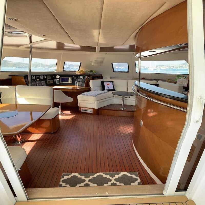 a room with a wood floor and a couch and a table with a laptop on it aboard VIVO Yacht for Charter