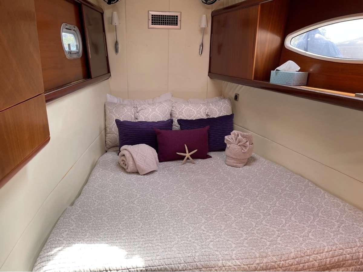 a bed with purple pillows aboard VIVO Yacht for Charter