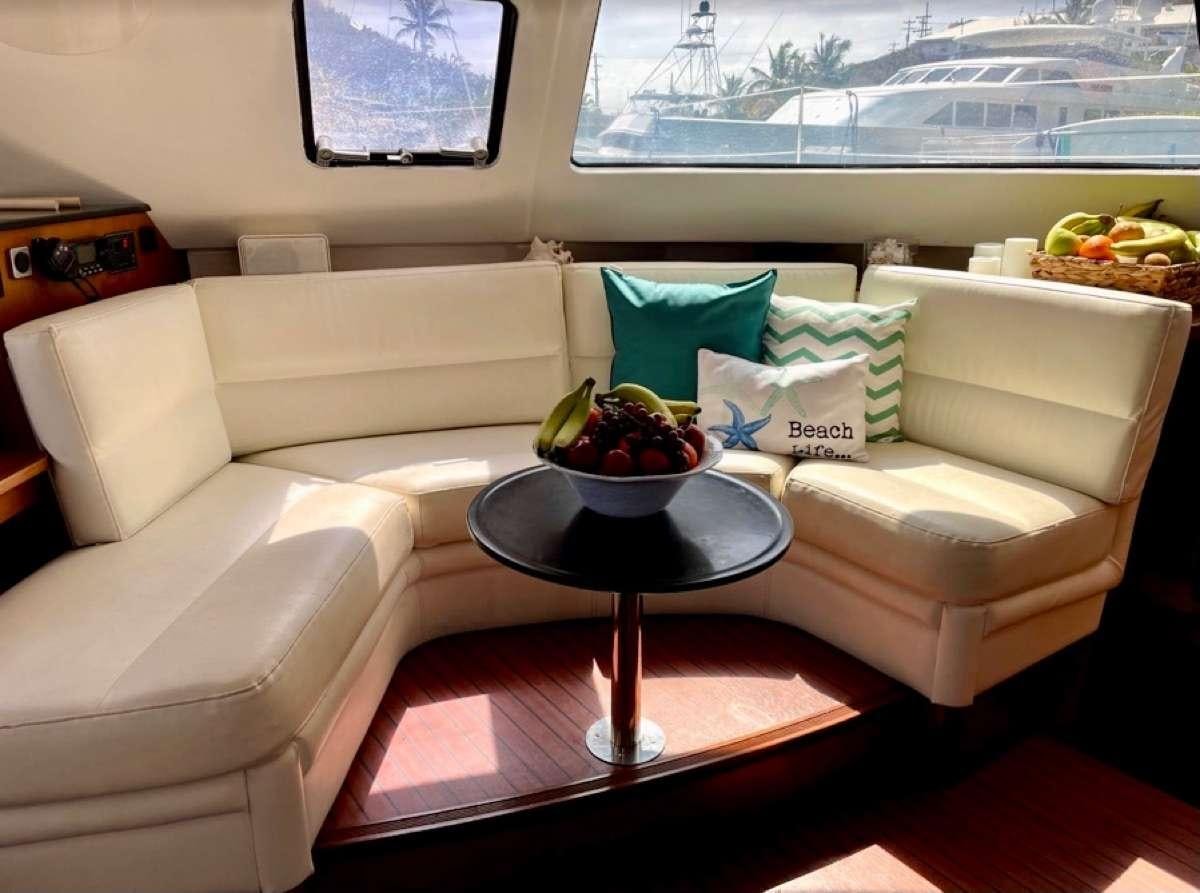 a white couch with a bowl of fruit on it aboard VIVO Yacht for Charter
