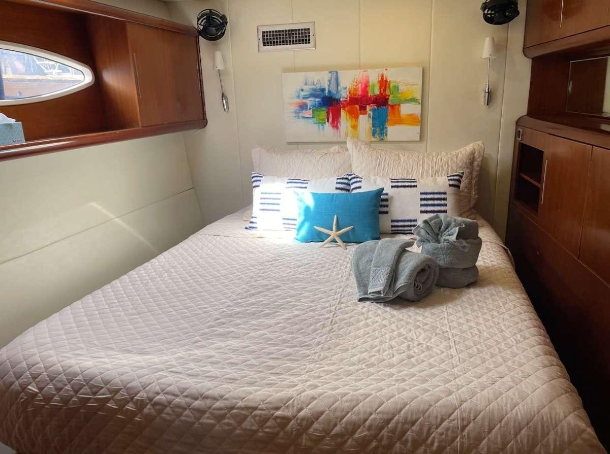 a bed with a white sheet and pillows on it aboard VIVO Yacht for Charter