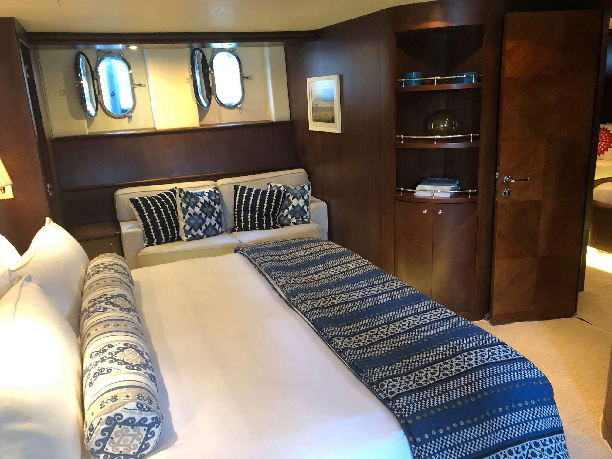 a bed with a white sheet and pillows in a room with a wood cabinet and a mirror aboard REFLECTIONS Yacht for Charter