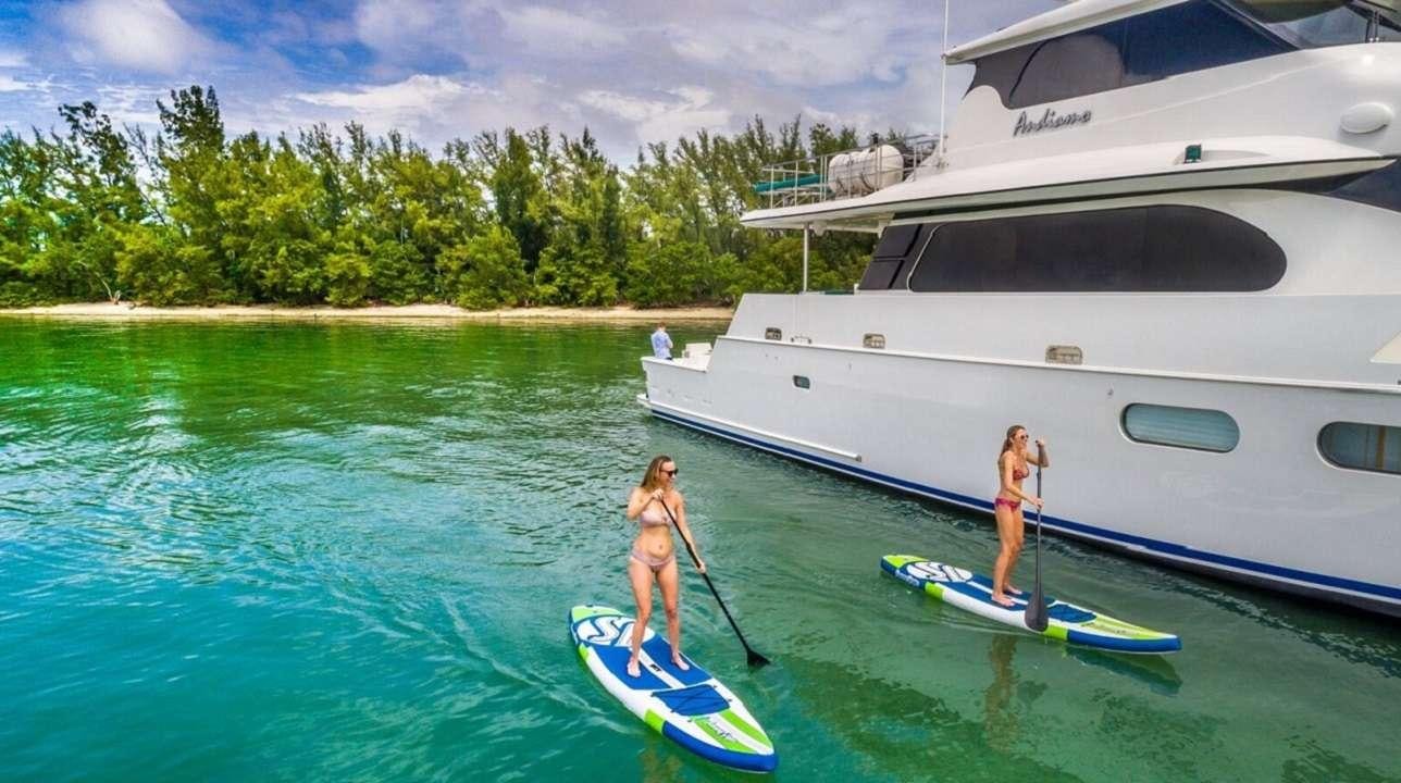 a person and a child on a surfboard in a tropical bay aboard ANDIAMO Yacht for Charter