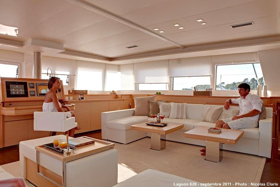 a man and a woman sitting on a couch in a room with a coffee table and a window aboard FIREFLY Yacht for Charter