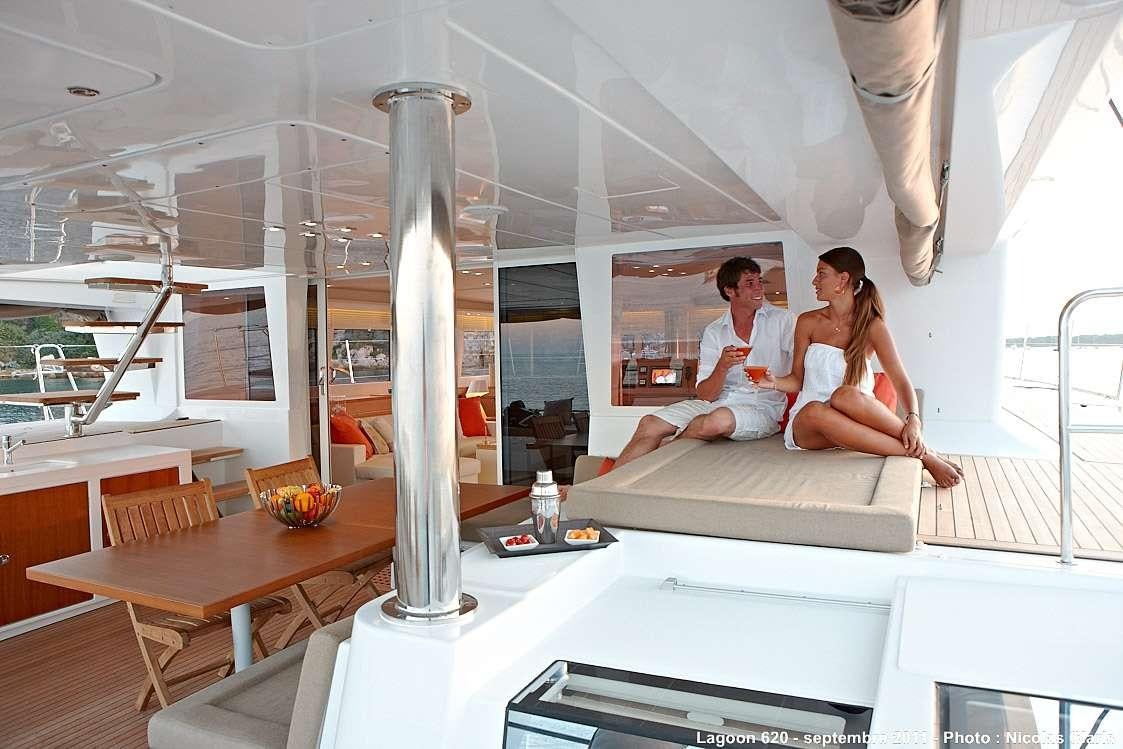 a man and a woman sitting on a couch in a room with a large pillar and a lamp aboard FIREFLY Yacht for Charter