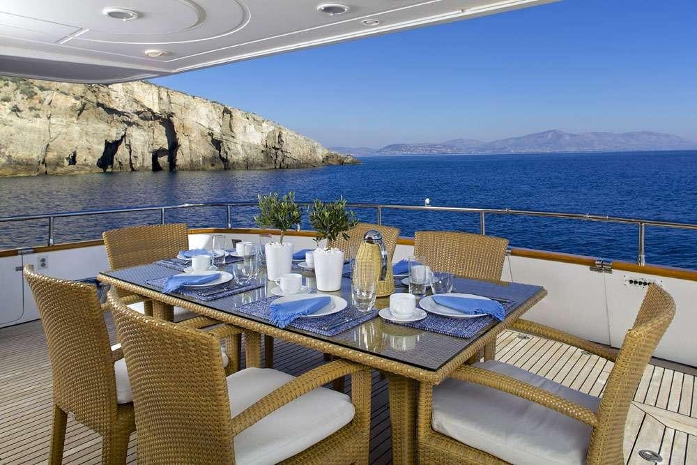 a table set for a meal on a balcony overlooking the ocean aboard LET IT BE Yacht for Charter