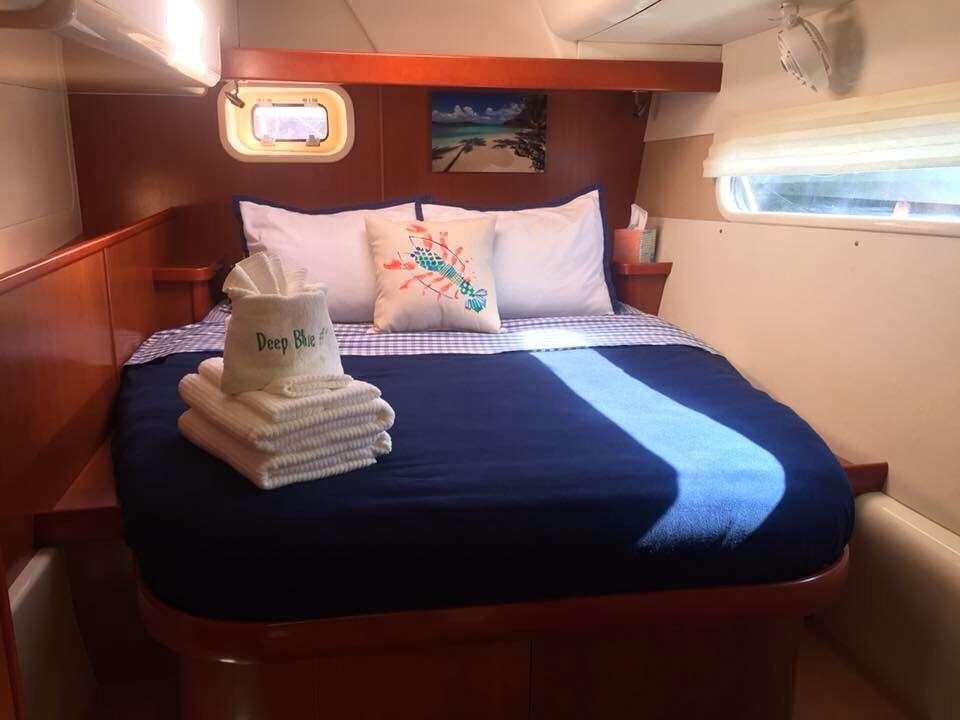 a bed with blue sheets and pillows aboard DEEPBLUE Yacht for Charter