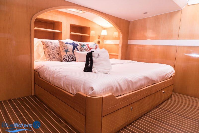 a bed with white sheets and pillows aboard LUAR Yacht for Charter