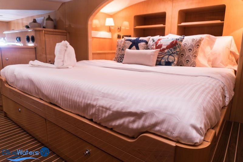a bed with white sheets and pillows aboard LUAR Yacht for Charter