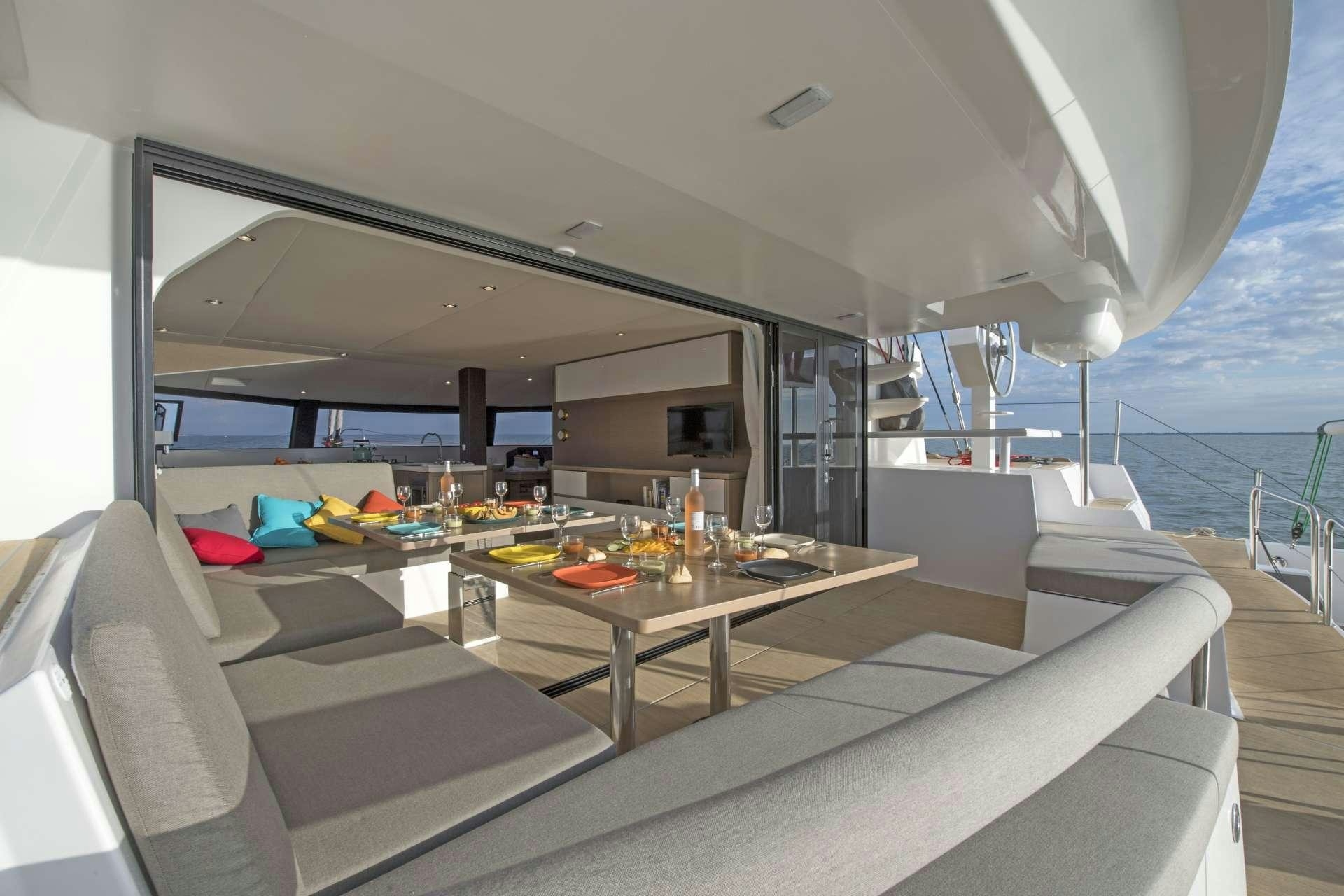 a room with a couch and a table with a glass window aboard TRILOGY Yacht for Charter