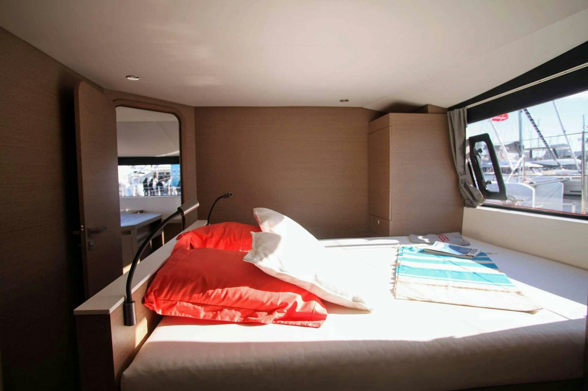 a bed with a red pillow aboard TRILOGY Yacht for Charter