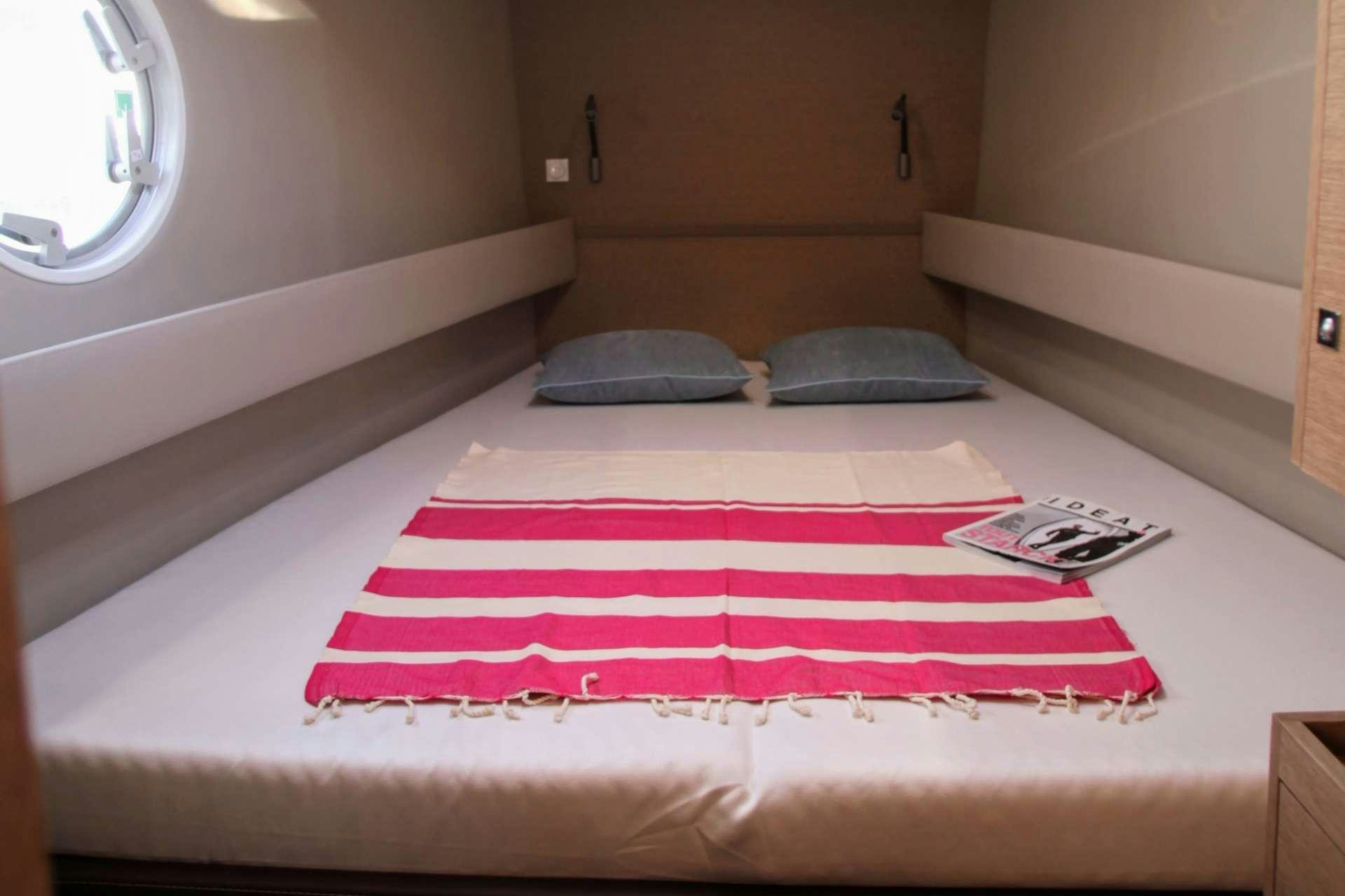 a bed with a red and white striped sheet and a pillow on it aboard TRILOGY Yacht for Charter