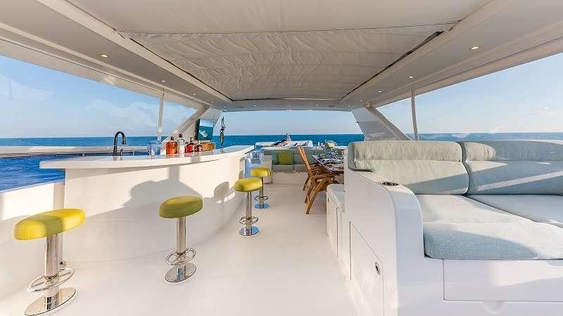 a room with a white couch and stools and a table aboard HIGH RISE Yacht for Charter