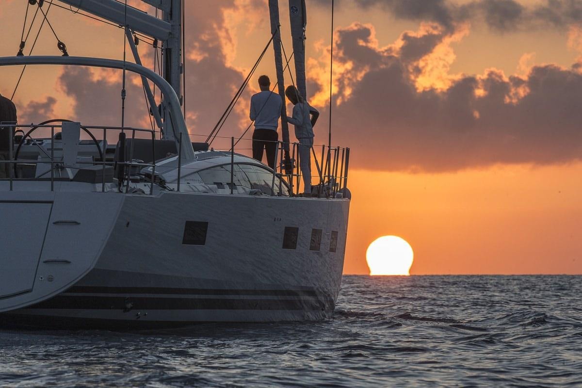 a couple of people standing on a boat in the water aboard JEANNEAU 64 Yacht for Charter