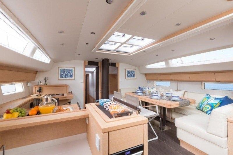 a kitchen with a table and a couch aboard JEANNEAU 64 Yacht for Charter