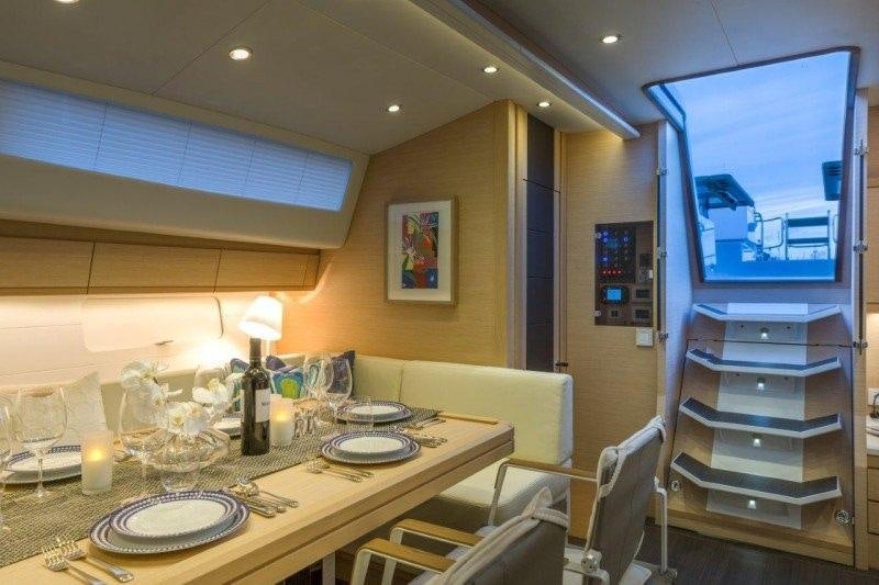a dining table with plates and glasses aboard JEANNEAU 64 Yacht for Charter