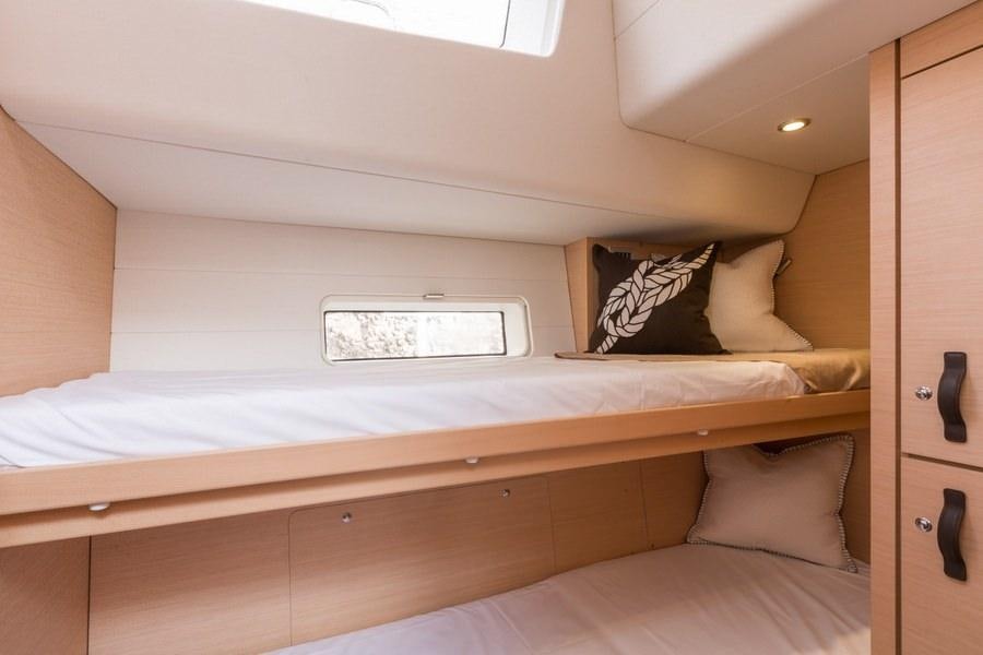 a bed with a white pillow aboard JEANNEAU 64 Yacht for Charter