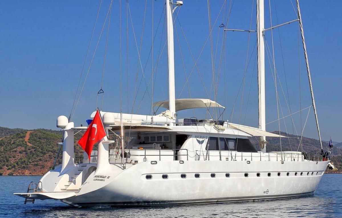 a white boat with a red flag on it aboard ANGELO II Yacht for Charter