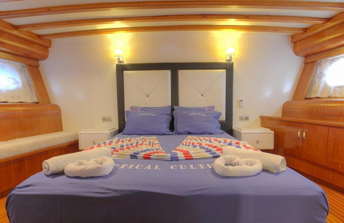 a bed with blue sheets aboard ANGELO II Yacht for Charter