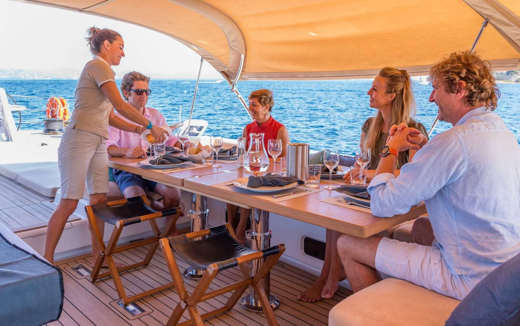 a group of people sitting around a table on a boat aboard THALIMA Yacht for Charter
