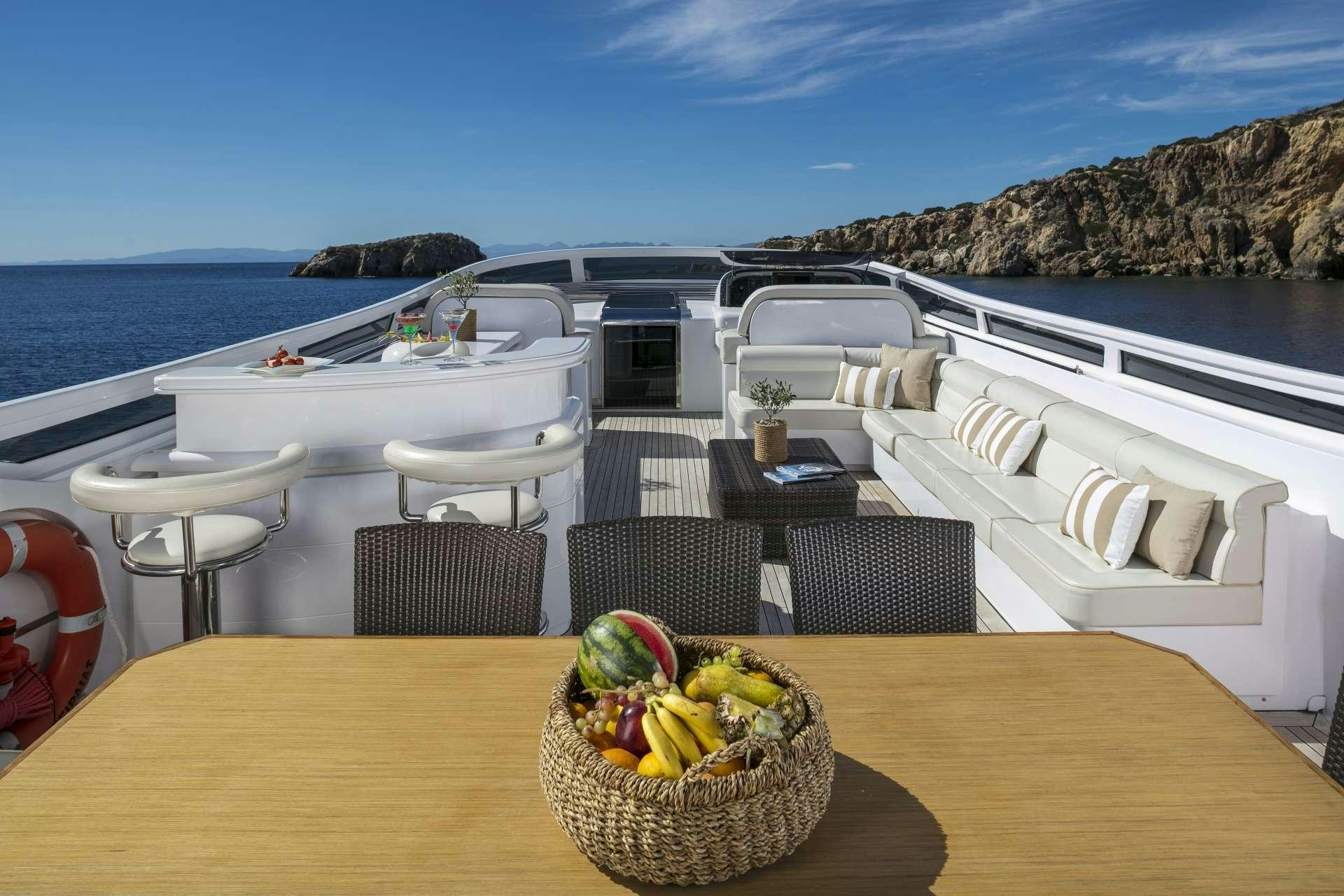 a table with chairs and a basket of fruit on it aboard ANASA Yacht for Charter