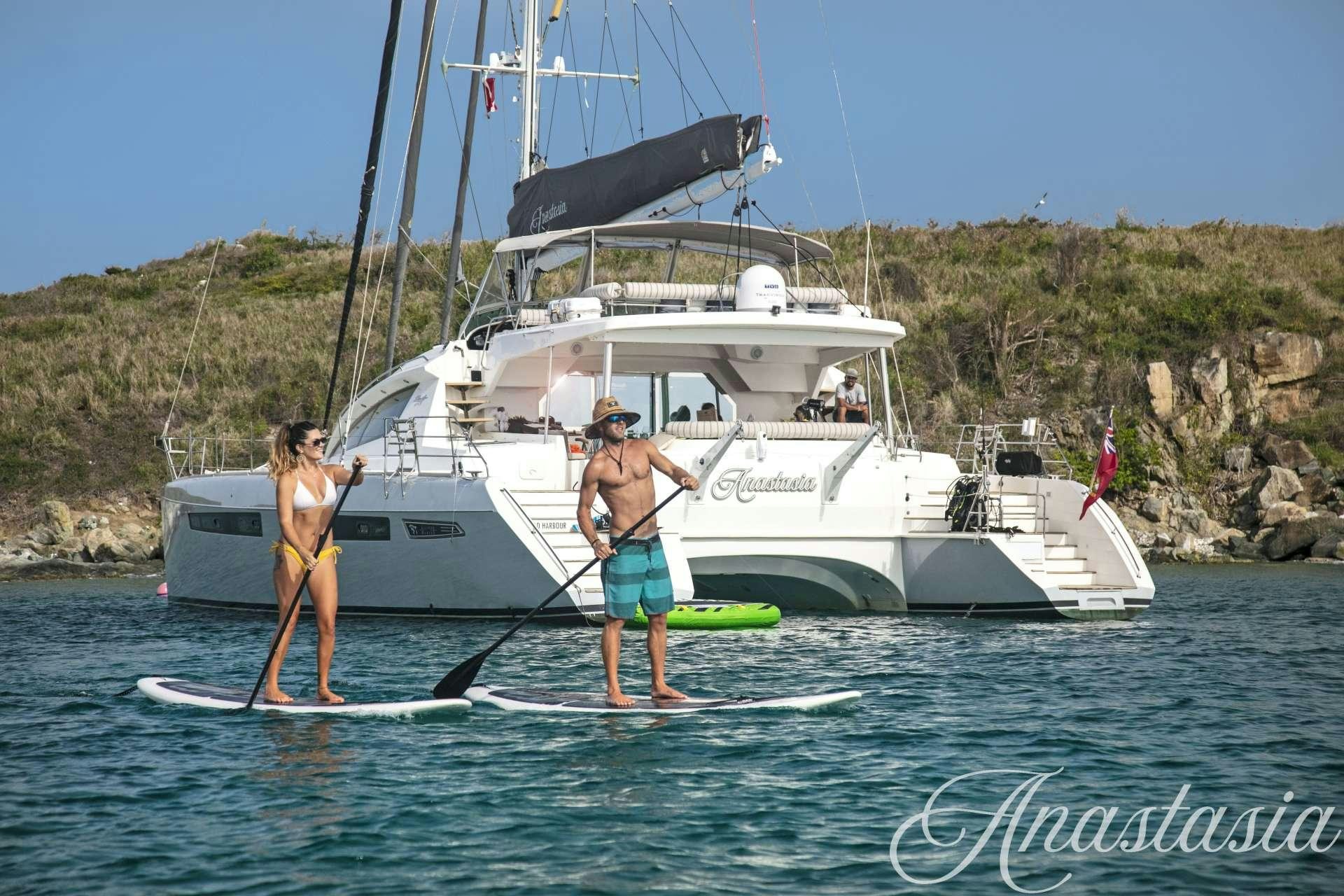 a couple of people stand on a surfboard in front of a boat aboard SWEET ANN MARIE Yacht for Charter