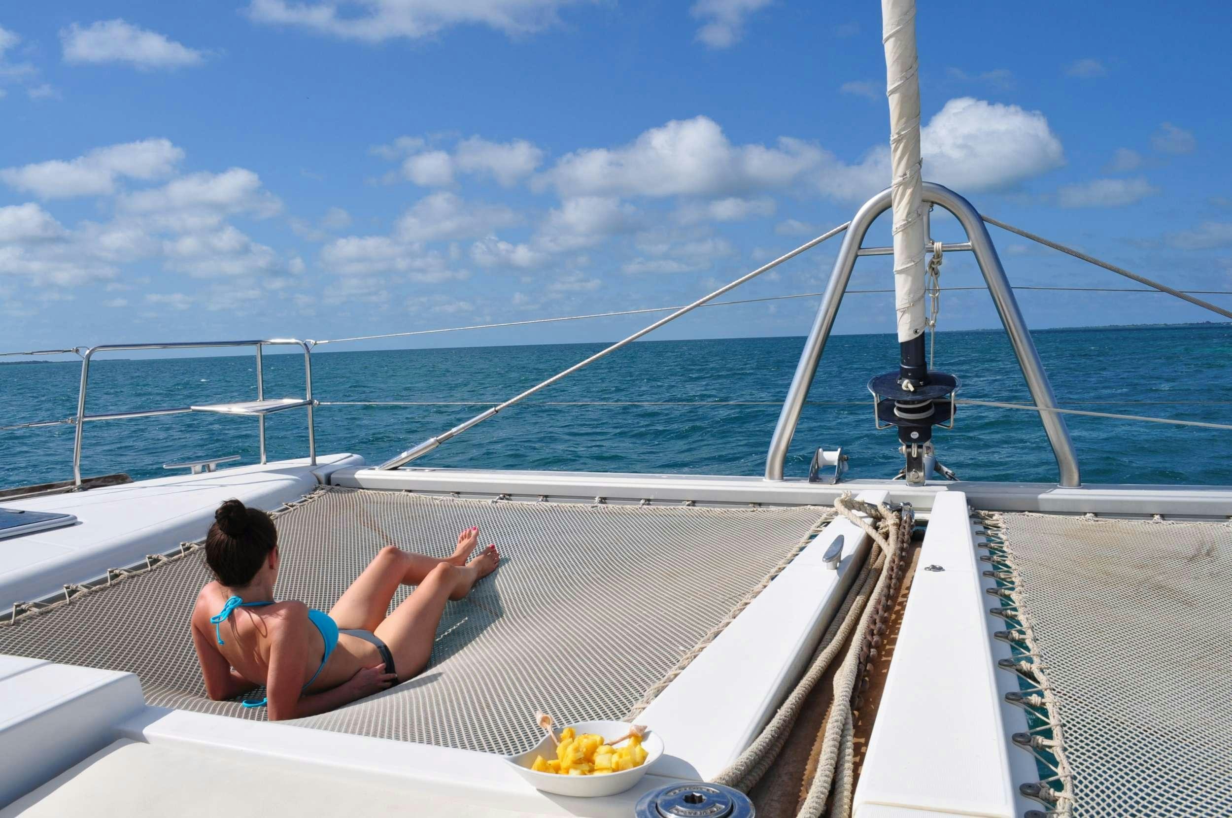 a person lying on a deck on a boat with a bowl of fruit aboard DORIS Yacht for Charter