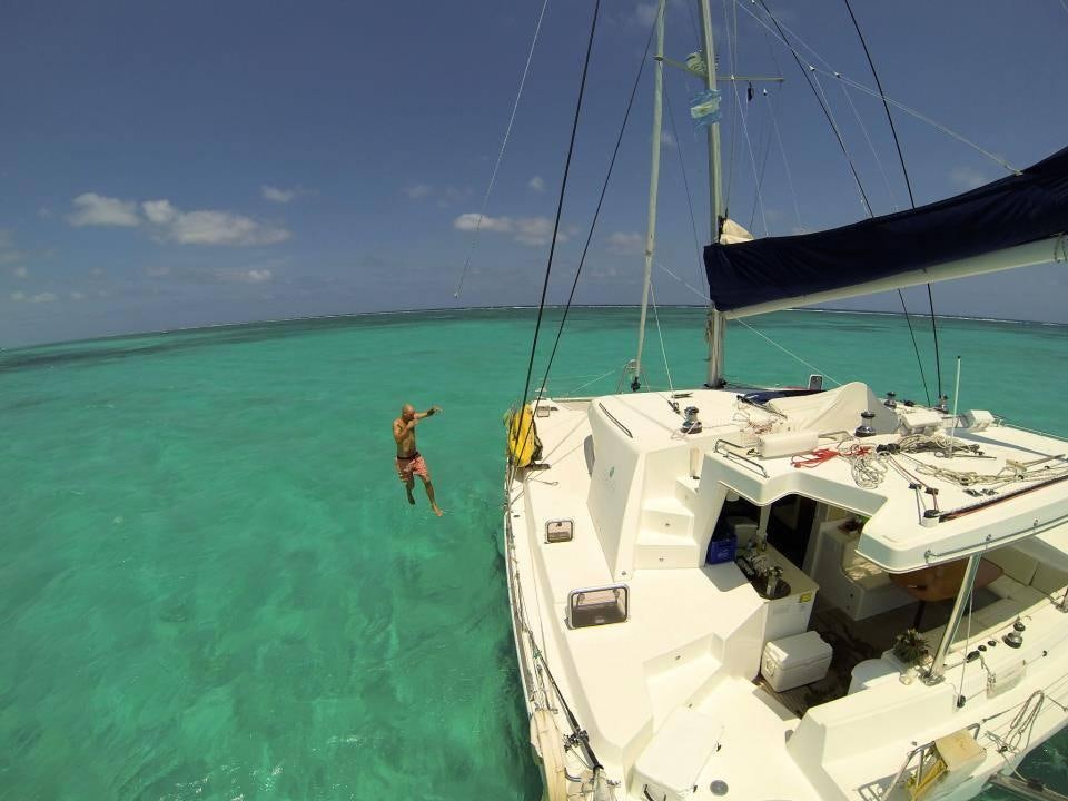a person jumping into a body of water next to a boat aboard DORIS Yacht for Charter
